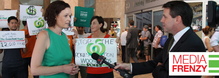Allison talking to a journalist with a Channel 7 microphone, people holding signs in the background, caption reads Media Frenzy