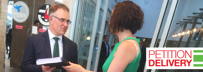 Allison handing over the petition to Woolworths executive, caption reads Petition Delivery