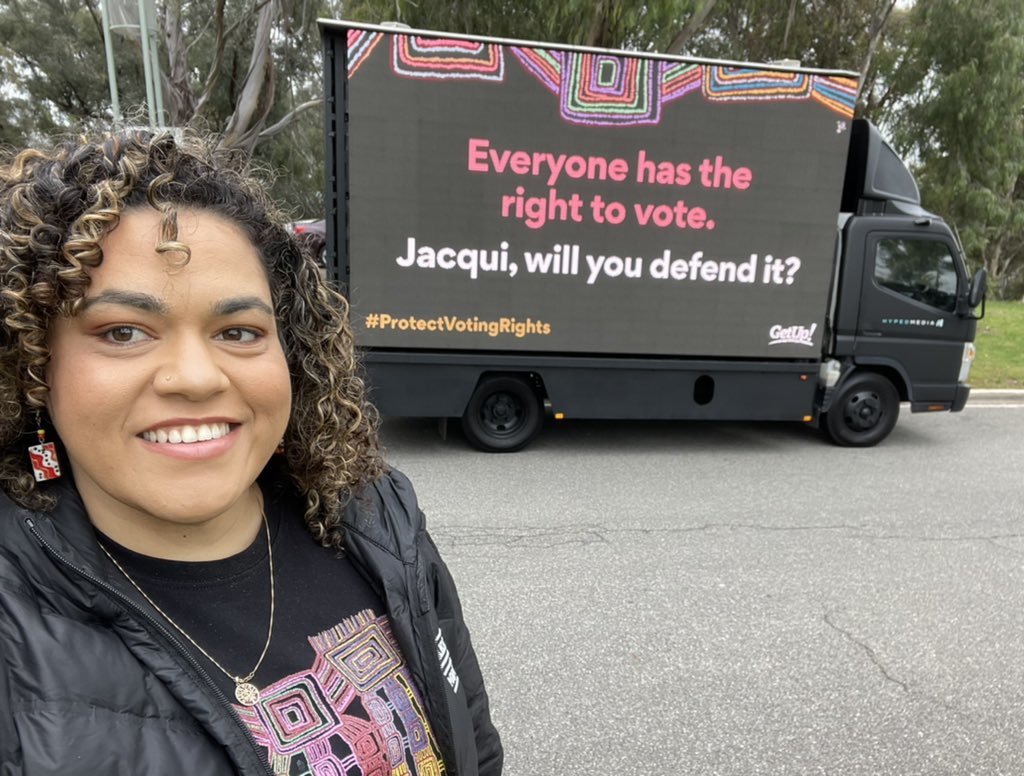 GetUp's First Nations Justice Campaign Director in front of a billboard on voter ID