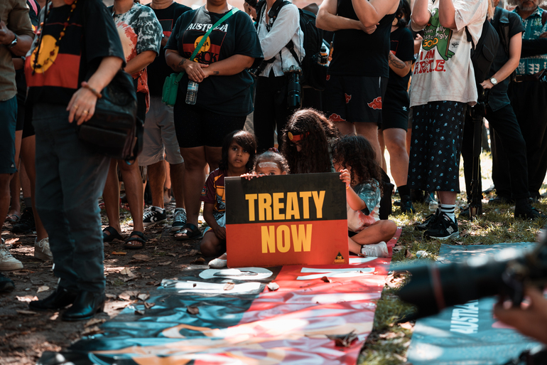 Kids holding a 'treaty now' sign at Invasion Day Sydney 2023